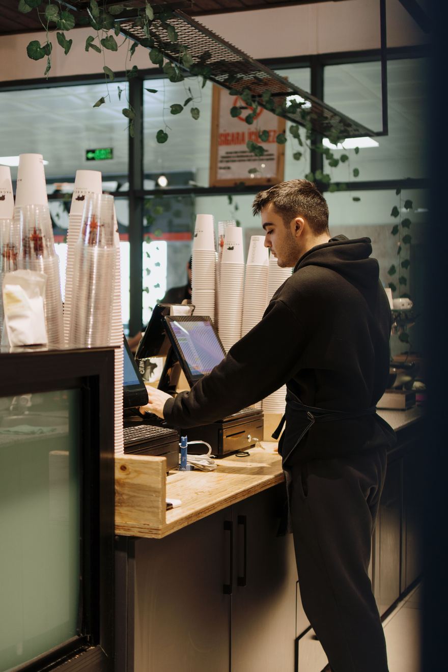 Empleado de cafetería usando el punto de venta en el mostrador
